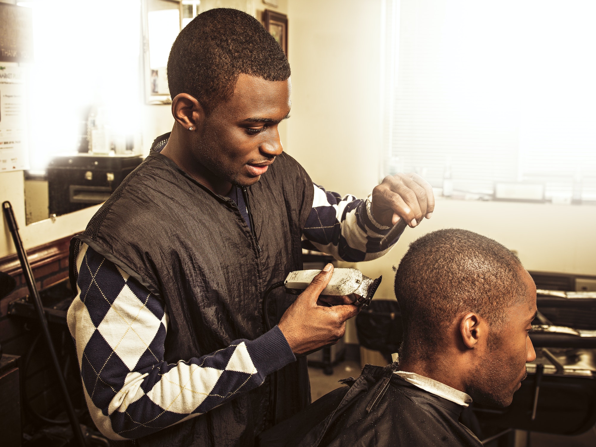 Barber in traditional barber shop shaving man's head